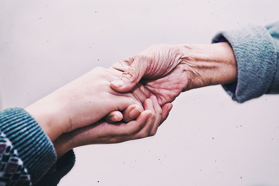 Close up on young hands holding old hand.